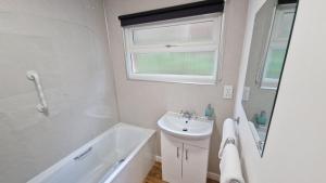 ein weißes Badezimmer mit einem Waschbecken und einer Badewanne in der Unterkunft 6 The Dunes in Braunton