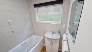 a white bathroom with a sink and a bath tub at 6 The Dunes in Braunton +8 photos