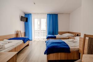 1 Schlafzimmer mit 2 Betten und einem Fenster mit blauen Vorhängen in der Unterkunft Centrum Wypoczynku i Rekreacji Rysy Krynica Zdrój in Krynica-Zdrój
