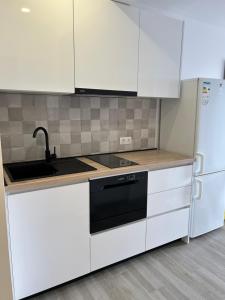 a kitchen with white cabinets and a black dishwasher at Apartmani Peco Duće in Duće