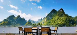 a table and chairs with mountains in the background at Melody Inn in Yangshuo