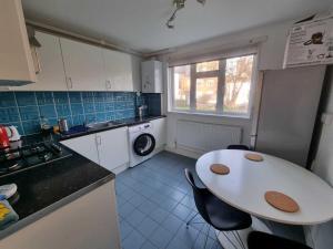 uma pequena cozinha com uma mesa e um lavatório em 2 Bedroom Apartment in Kentish Town em Londres