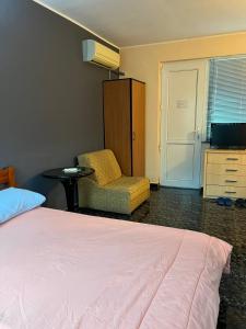 um quarto com uma cama, uma cadeira e uma televisão em Guest House Dobrev em Kardzhali