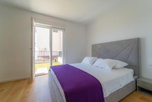 een slaapkamer met een groot bed en een groot raam bij Apartman Dvor in Podstrana