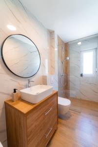uma casa de banho com um lavatório, um espelho e um WC. em Apartman Dvor em Podstrana
