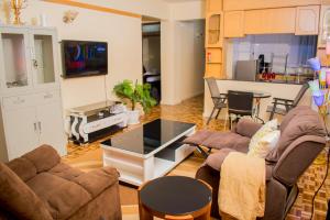 a living room with two couches and a kitchen at G&G Homes Executive 2 bedroom Town Apartment in Eldoret