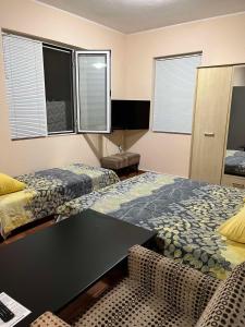 1 dormitorio con 2 camas, escritorio y ventanas en Guest House Dobrev, en Kardzhali