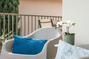 einen weißen Stuhl mit einem blauen Kissen auf dem Balkon in der Unterkunft Il lago dei Sogni - Stupenda Vista Lago e Colline in Barcuzzi