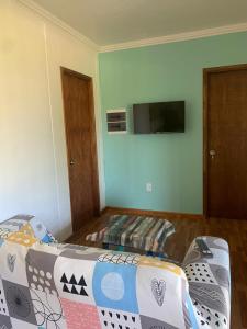 een slaapkamer met een bed en een flatscreen-tv bij CANDELA casa en balneario Los Pinos II in Fomento