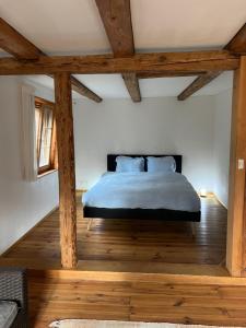 um quarto com uma cama, pisos em madeira e vigas em madeira em Alpen Oase Natur em St. Gallen