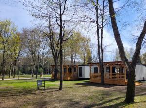 una cabaña en un parque con árboles y un banco en Thermal Camping Zalakaros, en Zalakaros