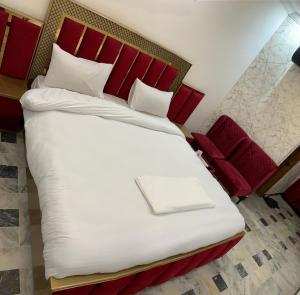 a bedroom with a large bed with a red headboard at Hotel Flower of Capital in Islamabad
