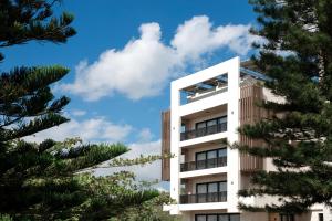 a tall white building with trees in the foreground at Camp David Ranch in Santiago de los Caballeros