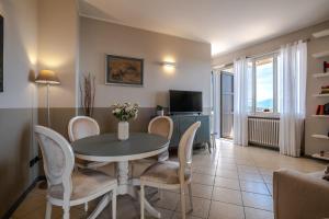 ein Wohnzimmer mit einem Tisch, Stühlen und einem TV in der Unterkunft Il lago dei Sogni - Stupenda Vista Lago e Colline in Barcuzzi