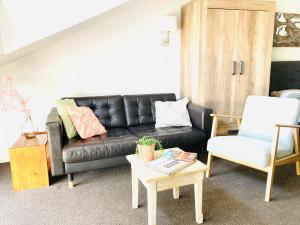uma sala de estar com um sofá de couro preto e uma mesa em Nicolette Apartments em Katwijk