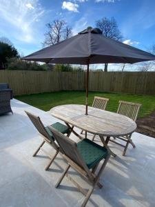 a table and chairs with an umbrella on a patio at Peaceful Woodland Retreat near Clifton, Bristol in Bristol