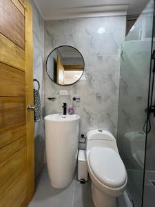 a bathroom with a toilet and a sink and a mirror at Apartamento centro de la ciudad in San Pedro de Macorís