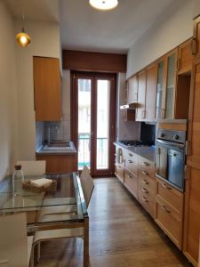 kuchnia z drewnianymi szafkami i szklanym stołem w obiekcie Massi’s House w Mediolanie