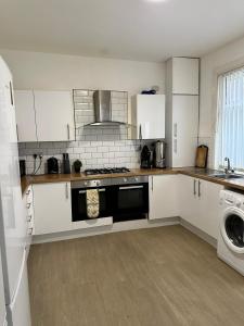 a kitchen with white cabinets and a stove top oven at Quirky Oasis Anfield in Liverpool