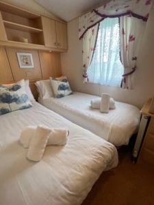 2 camas en una habitación pequeña con ventana en Cuddfan, en Llanrhystyd