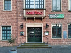 ein Backsteingebäude mit einer Tür und einem Donut-Shop in der Unterkunft DORMERO Hotel Xanten in Xanten