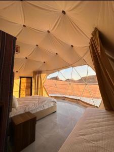 a bedroom with two beds and a view of the desert at camp scylla Wadi Rum in Wadi Rum
