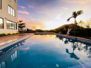 Zestin Hill Resort Lonavala في لونافالا: مسبح كبير مع غروب الشمس في الخلفية