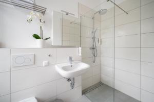La salle de bains blanche est pourvue d'un lavabo et d'une douche. dans l'établissement Servus Apartments by Homaris, à Munich