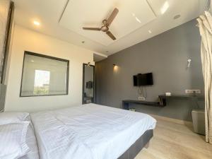 Zestin Hill Resort Lonavala في لونافالا: غرفة نوم بسرير أبيض ومروحة سقف