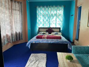 um quarto com uma cama com paredes azuis e uma janela em Pradhan Homestay Mirik - Homestay beside Mirik Lake em Mirik