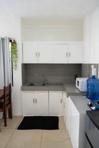 a kitchen with white cabinets and a sink at Amara Pool & Villas 180Mbps Central location in General Luna