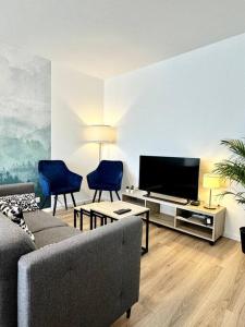 a living room with a couch and a flat screen tv at Le Spot, proche Euroairport in Saint-Louis