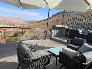 a patio with two chairs and a table and an umbrella at Modern 2BR Duplex in Afqā