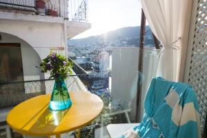 un jarrón de flores sentado en una mesa en un balcón en Gruccio Yellow Studio - A Sunny Skiathos Gem, en Skiathos