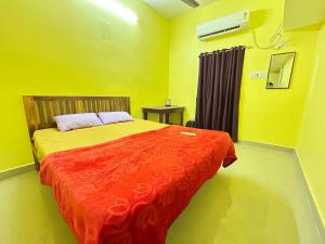 a bedroom with a bed with a red comforter at SELVAS BUDGET STAY in Puducherry