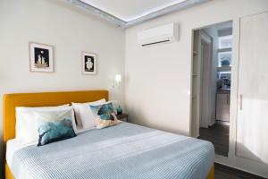 1 dormitorio con 1 cama con almohadas azules y blancas en Gruccio Yellow Studio - A Sunny Skiathos Gem, en Skiathos