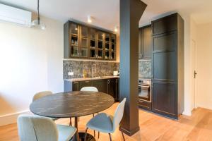 a kitchen with a table and chairs and a black refrigerator at Appart 6Pers # Père Lachaise # Voltaire # Paris 11 in Paris