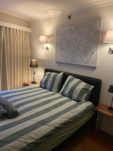 Schlafzimmer mit einem Bett mit blauen und weißen Streifen in der Unterkunft Centraal gelegen gezellig verblijf met groot terras in Ostende