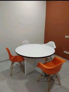 una mesa blanca y 2 sillas naranjas en una habitación en Loft Puente Romano, en Salamanca