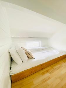 Bett mit weißer Bettwäsche und Kissen in einem Zimmer in der Unterkunft Primrose Hill Apartment with Balcony in London