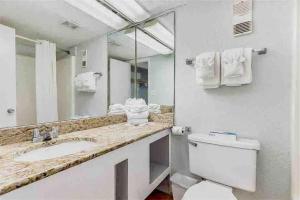 a bathroom with a toilet and a sink and a mirror at Oceanfront. Ground Floor. Easily Accessible. in Myrtle Beach
