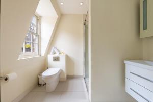 a white bathroom with a toilet and a window at The Shepherd Residence in London