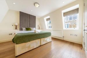 a bedroom with a bed with a green blanket and two windows at The Shepherd Residence in London