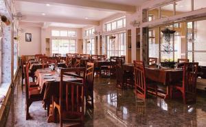 comedor con mesas y sillas de madera en La Nicholas Lake View by Summit Hotels, en Mawlyngkhung