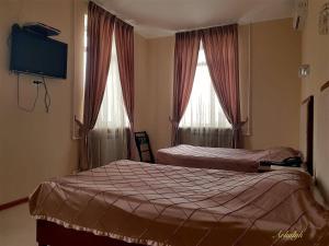 a bedroom with two beds and a tv and two windows at гостиница Аркалык in Arqalyq
