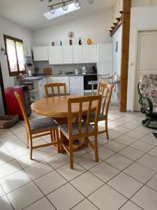 eine Küche mit einem Holztisch und Stühlen sowie eine Küche mit weißen Schränken in der Unterkunft Le Gîte de Jules en Meuse à VIGNOT près de MADINE in Vignot