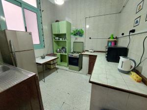 cocina con armarios verdes y nevera en AL- Mazareta a private room at Shared apartment For Men only No Ladies allowed غرفة خاصة في شقة مشتركة للرجال فقط ممنوع السيدات仅限男士 女士不允许, en Alejandría