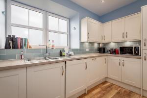a kitchen with white cabinets and a sink at Golf Course View Apartment - Craighead - Crail in Crail