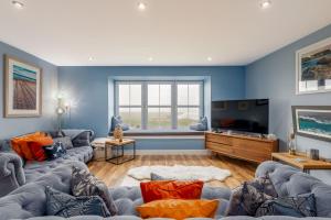 a living room with couches and a flat screen tv at Golf Course View Apartment - Craighead - Crail in Crail
