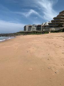 a beach with buildings in the background with footprints in the sand at Beachfront apartment in Ballito! Casablanca in Ballito